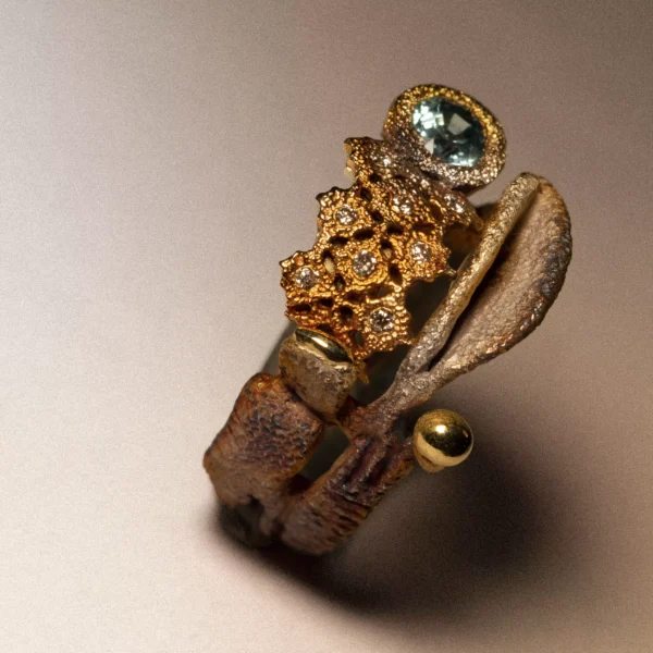Anello artigianale in argento ossidato con parti traforate in bronzo, zircone naturale azzurro, gocce d'oro e diamanti